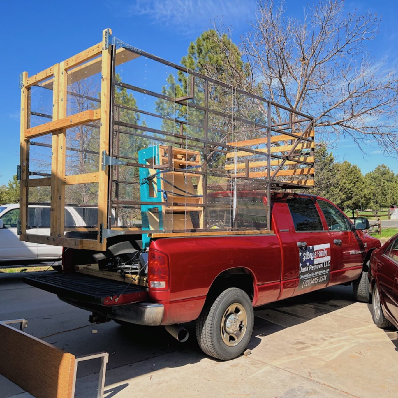 Red pickup truck with wooden frames and mesh structure loaded in the truck bed.