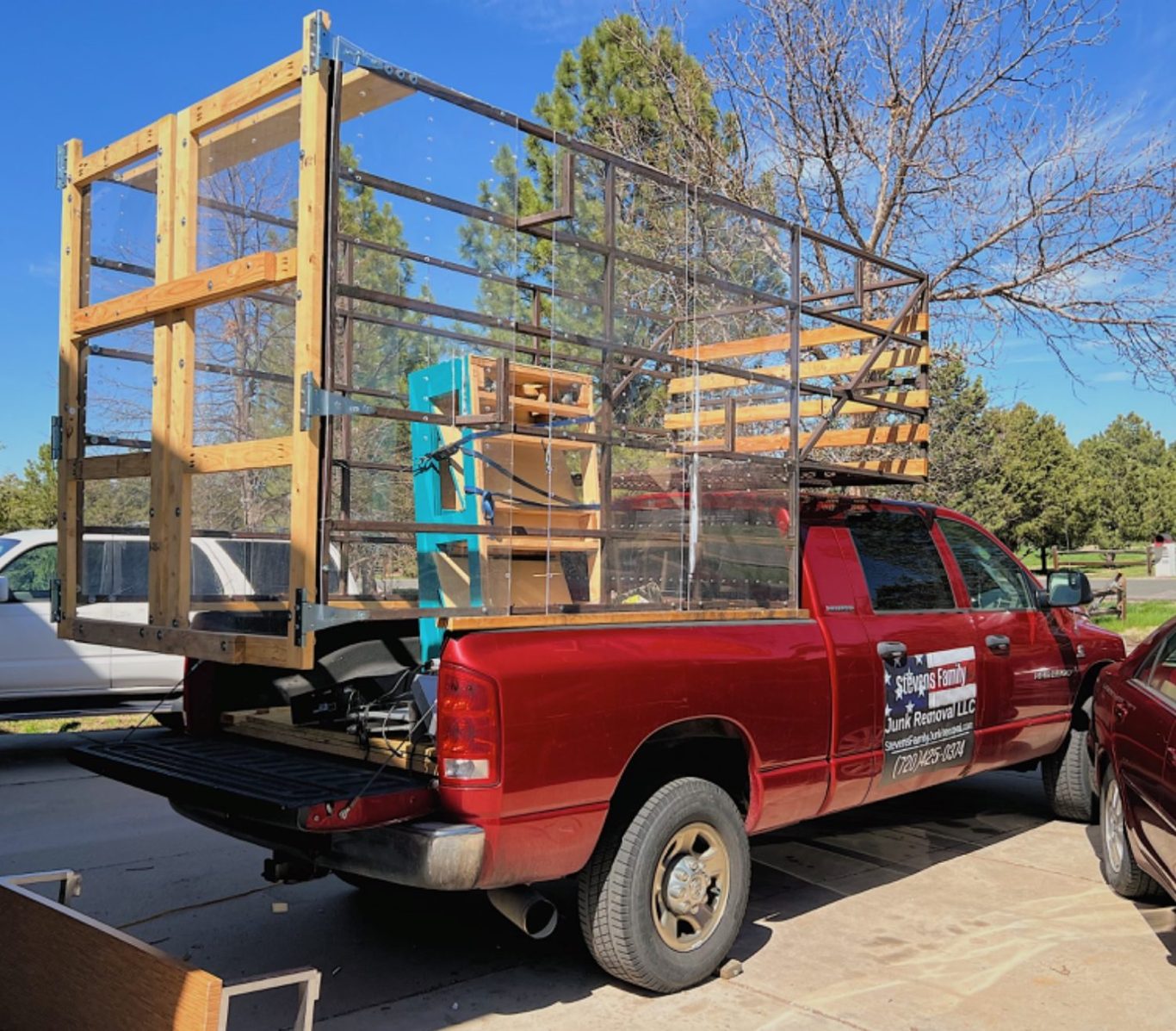 Red pickup truck with a wooden and metal cage structure on its bed.