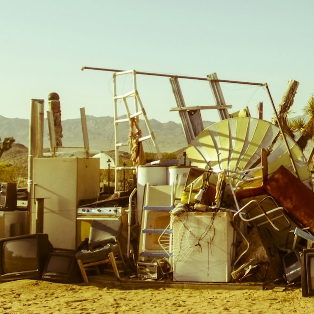 A pile of discarded furniture and appliances under a clear sky.